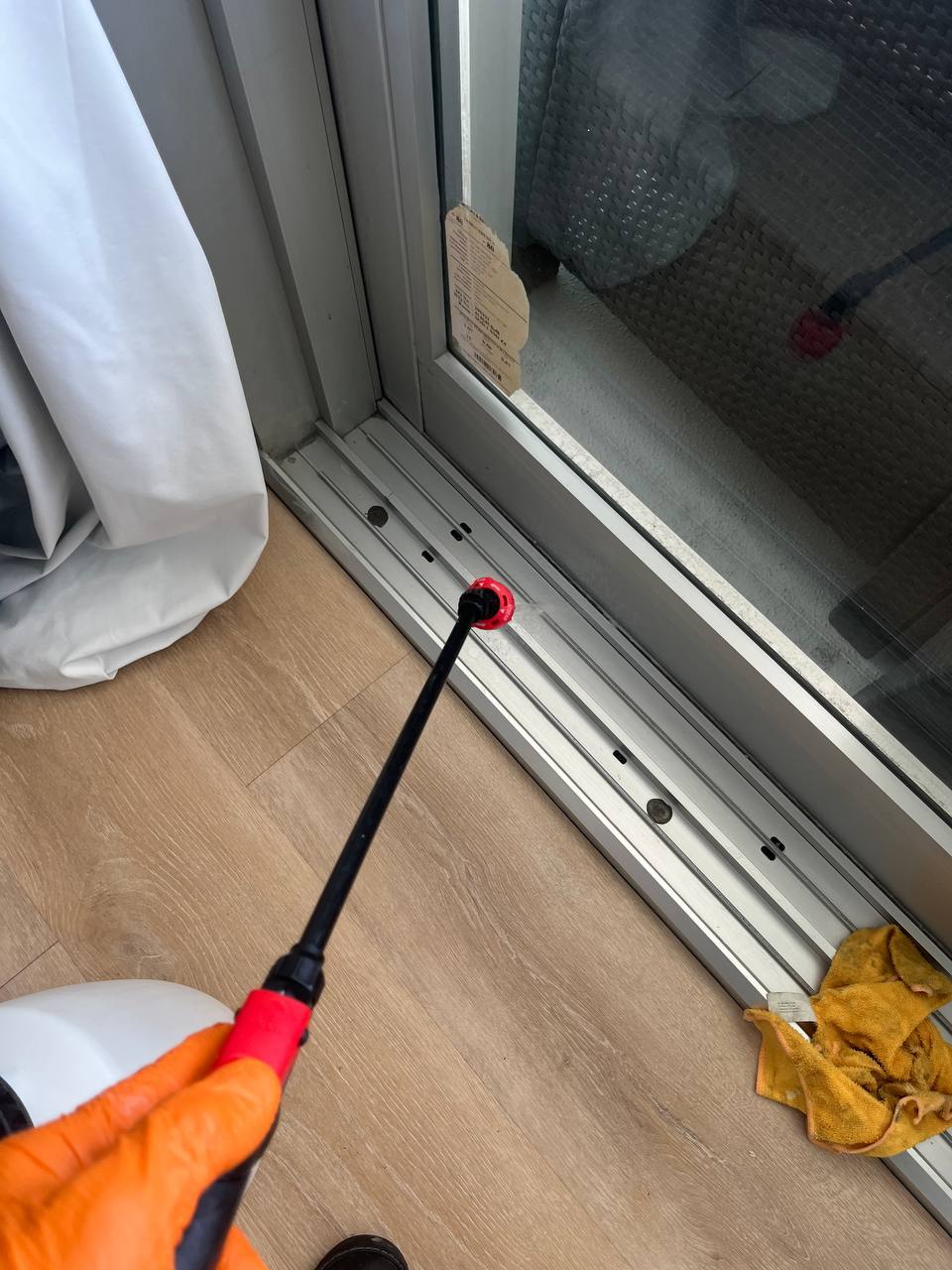 Technician applying cleaning solution to a sliding glass door track.