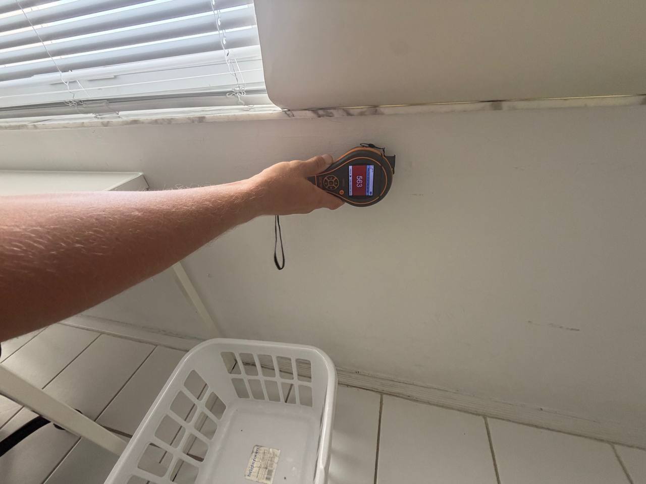 Technician using a moisture meter to inspect a bedroom wall during a free mold inspection.