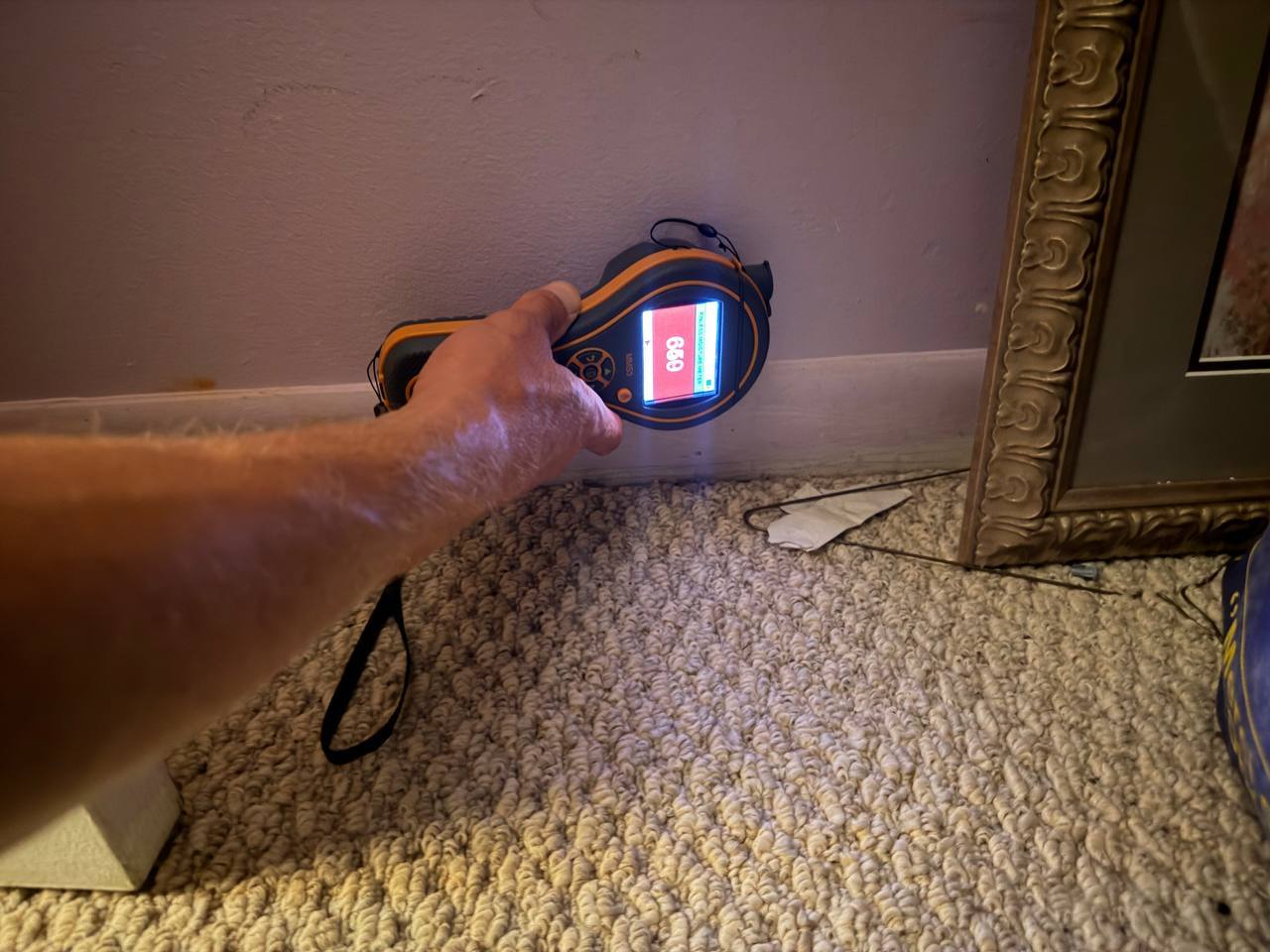 Moisture meter testing high dampness levels on drywall