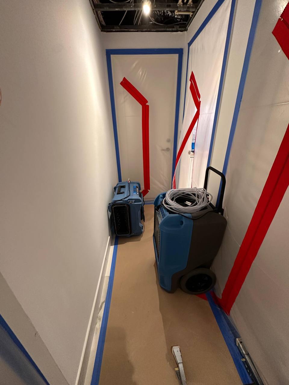 Commercial dehumidifier and air mover running inside plastic containment zone