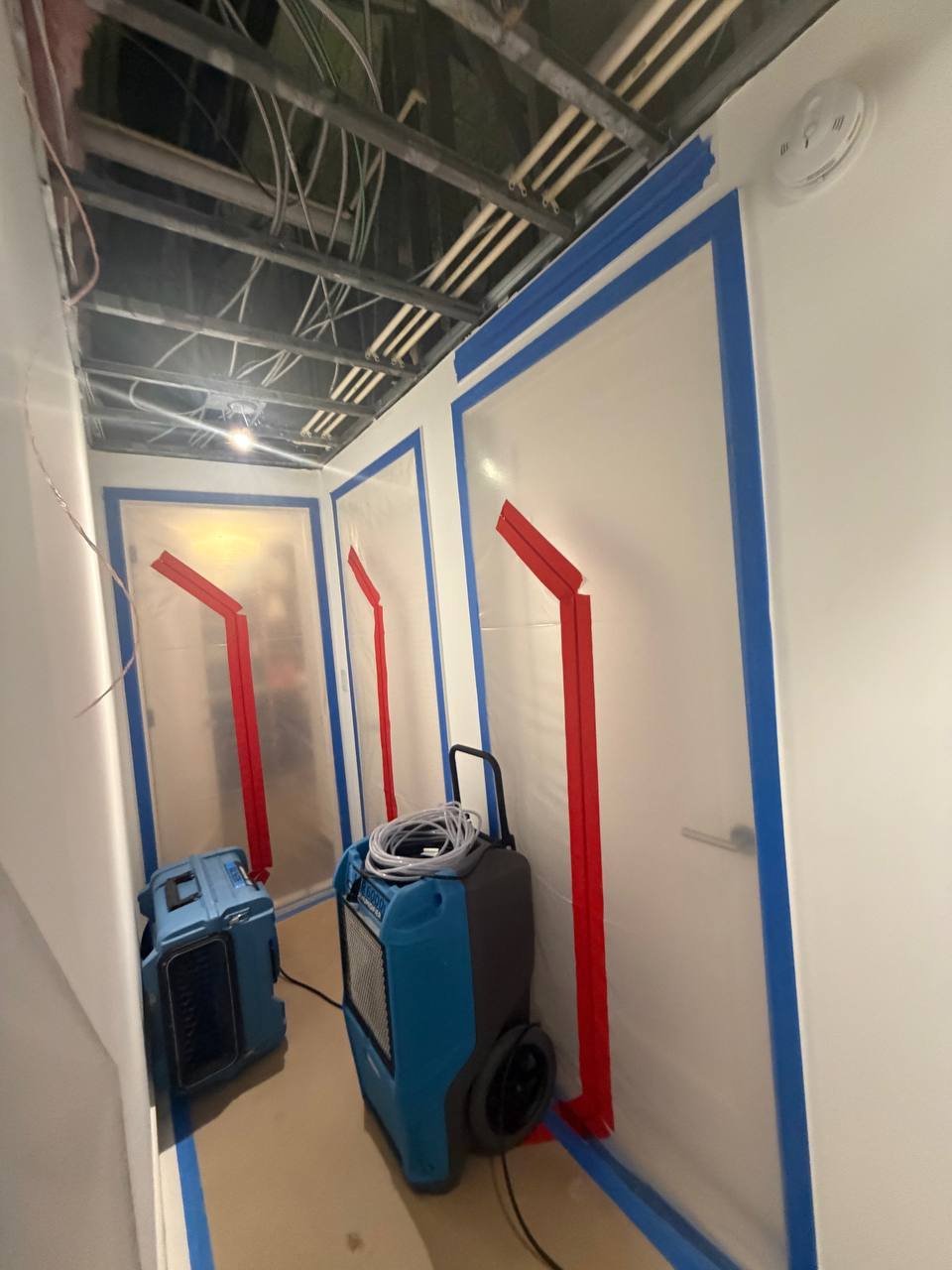 Commercial dehumidifier and air mover running inside plastic containment zone