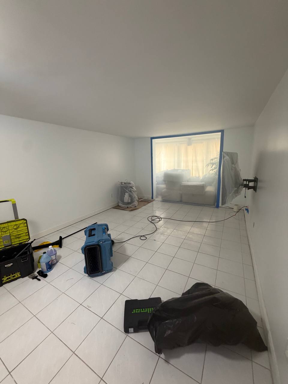 Plastic containment barrier and air movers set up in room for structural drying