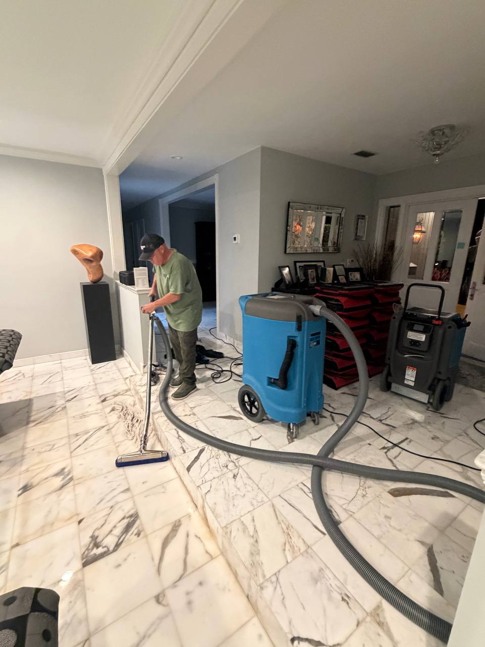 Technician performing heavy-duty water extraction on marble tile flooring