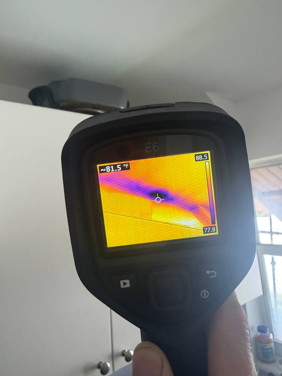 Thermal camera identifying cold moisture footprint from AC condensation leak along ceiling joint
