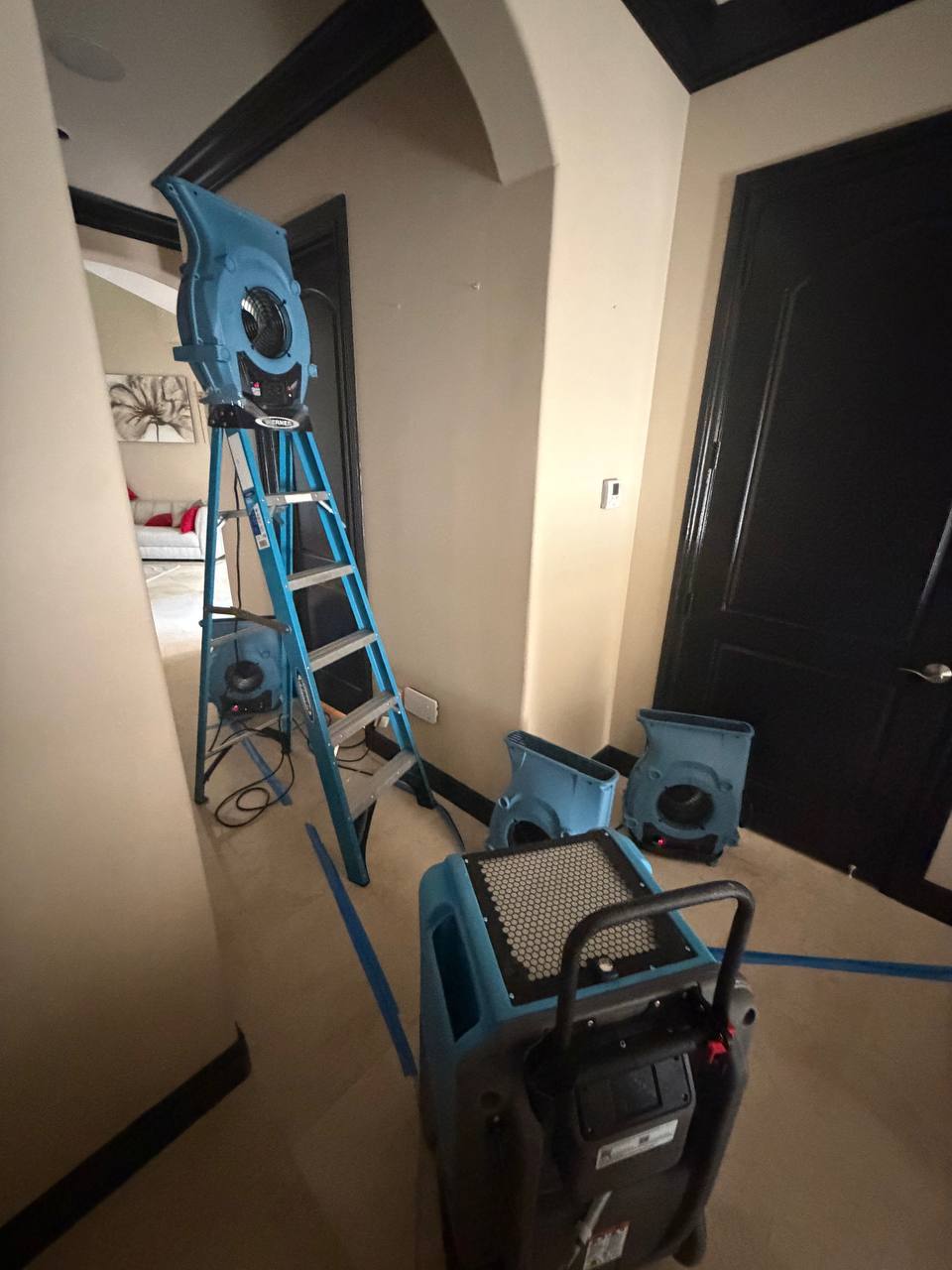 Commercial air movers and dehumidifiers set up for hallway wall drying in Davie home