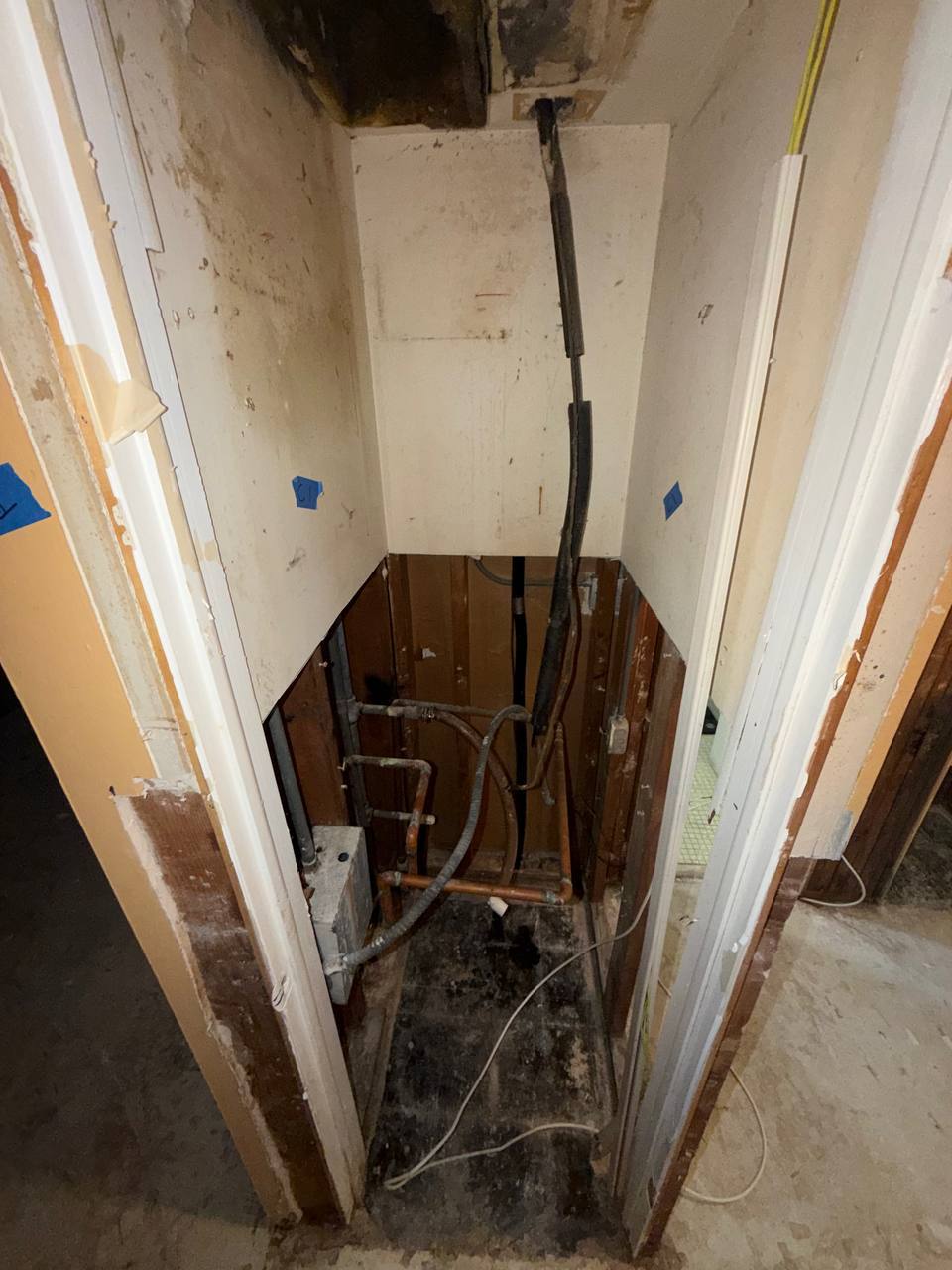 Exposed copper piping and treated framing inside AC and utility closet