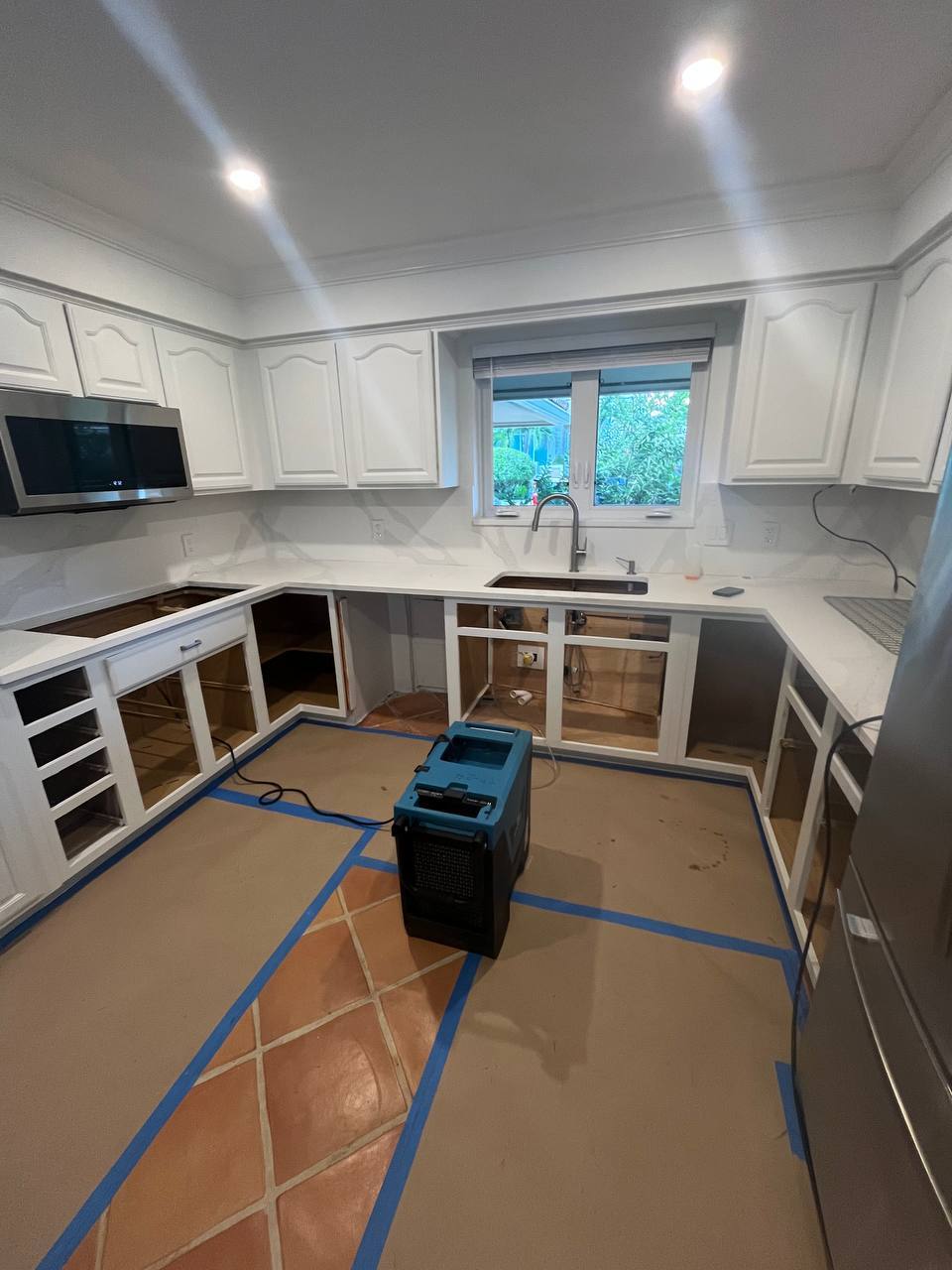 Commercial dehumidifier operating in kitchen during structural drying and mold treatment