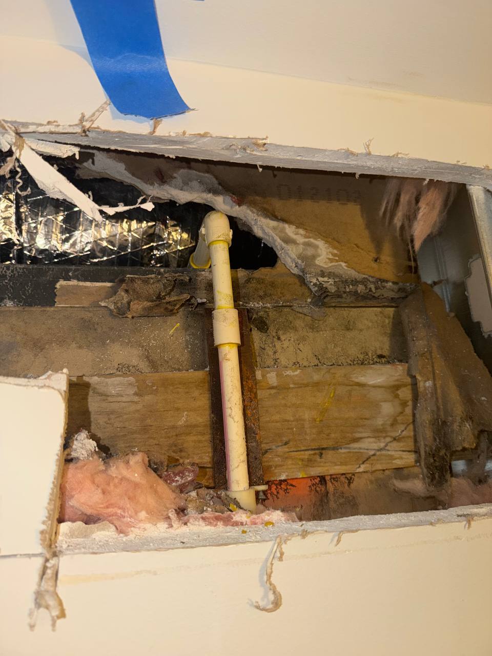 Exposed wall cavity showing internal plumbing pipe leak and water-damaged insulation